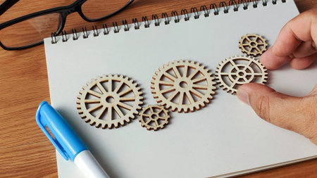 Hand Arranging Wooden Cogwheels on a Notebook: Conceptualizing Innovation, Problem Solving, and...