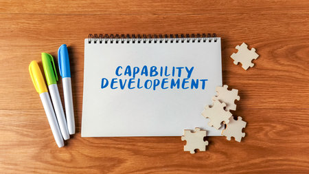 Capability Development text with markers and jigsaw puzzle pieces on a wooden desk symbolizing skill...