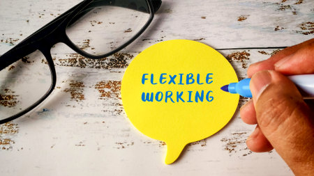 Flexible Working Schedule Concept with Hand Writing on Yellow Speech Bubble Note and Eyeglassesの写真素材