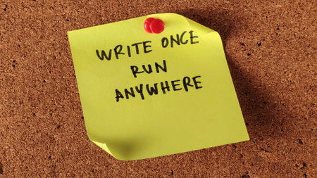 Yellow Sticky Note with Java Programming Motto "Write Once Run Anywhere" Pinned on Cork Boardの写真素材