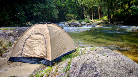 Adventure Tent Pitched Beside a Rocky River in a Deep, Lush Tropical Jungleの写真素材