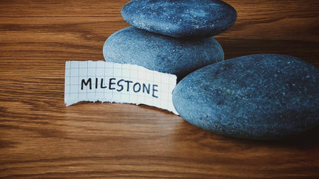 Stacked Stone Cairn with Handwritten Milestone Note on Dark Wood Background Symbolizing Progress and...