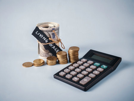 Calculator, Rolled Money, and Coins with Living Wage Text: Concept for Minimum Income Calculation,...
