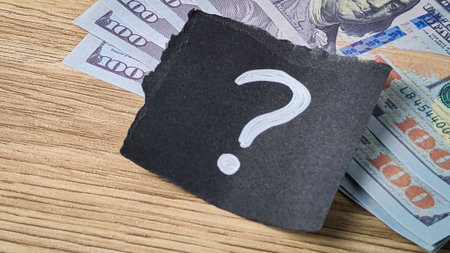 Financial Uncertainty Concept with Question Mark on Black Paper Resting on US Hundred Dollar Bills...