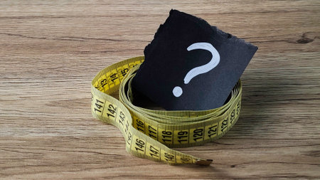 Weight Loss Question Concept with Yellow Measuring Tape and Question Mark on Black Paper on Wooden Backgroundの写真素材