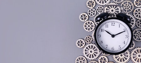 Alarm Clock and Wooden Gears Representing Time Management, Engineering, and Business Strategyの写真素材