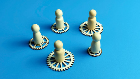 Concept of decentralized team or circular economy with wooden figures on gears in circular formationの写真素材