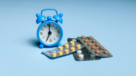 Medicine schedule and healthcare timing concept with blue alarm clock and blister packs of pills