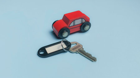 Red Wooden Toy Car with Silver Key and Tag for Automotive Sales and Rental Security Concept