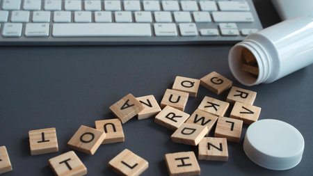 Wooden alphabet tiles and a pill bottle next to a computer keyboard representing online pharmacy, digital health, and medical blogging
