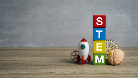 STEM education concept with colorful wooden blocks stacked vertically next to a toy rocket ship gears and a human brain model