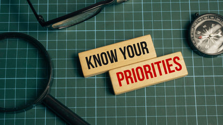 Know Your Priorities Text on Wooden Blocks with Compass Magnifying Glass and Eyeglasses on Green Cutting Mat