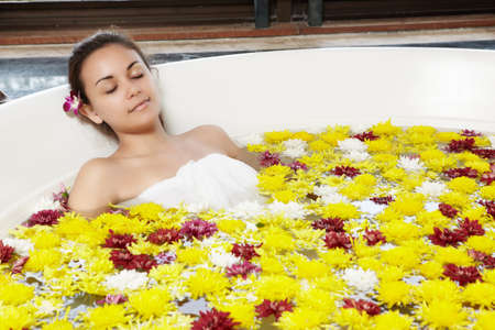 Close up of a young girl relaxing in the hot tub with full of flowerの写真素材