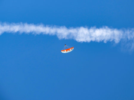 Paraglider in the sky with airplane condensation trail in the backgroundの写真素材