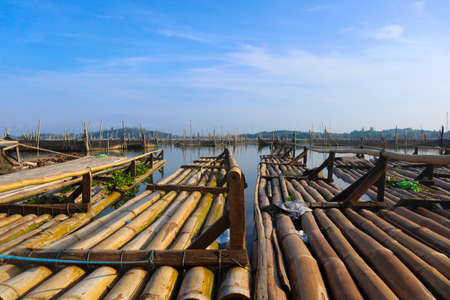 bamboo raft leaning against a lake among traditional fish cages in indonesia, asiaの写真素材