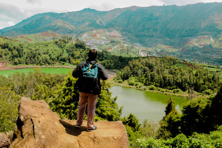 Young man standing on a rock of a cliff and enjoying the view of nature of lake and mountain.
symbol of freedomの写真素材