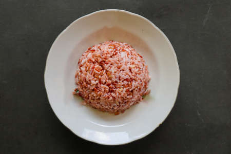 Red steamed rice or nasi merah served in plate isolated on black backgroundの写真素材