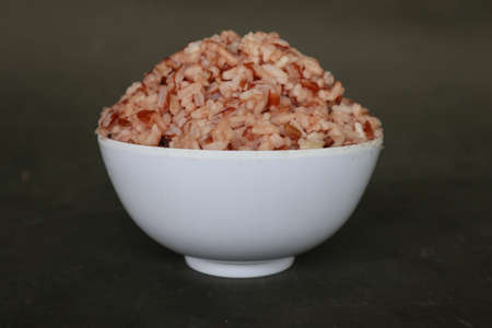 Red steamed rice or nasi merah served in plate isolated on black backgroundの写真素材