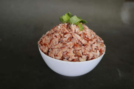 Red steamed rice or nasi merah served in plate isolated on black backgroundの写真素材