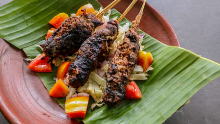 sate buntel or satay buntel is satay made from minced mutton wrapped in mutton fat and then grilled. seasoning with tomatoes, shallots, pepper, cabbageの写真素材
