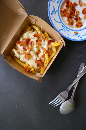 fried fries with with melted cheddar cheese or fried cheese with topping sausage slices on boxの写真素材