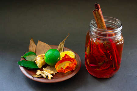 wedang uwuh is traditional herbal drink from indonesia.  made from cinnamon, nutmeg and cloves leaves. Another ingredient is wood from the secang tree, ginger and lump sugar on black backgroundの写真素材
