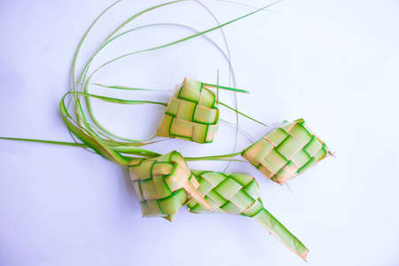 ketupat and rice at pottery bowl isolated  on white background. Ketupat (Rice Dumpling) food served when idhul fitri (eid mubarak) in Indonesia, made from rice wrapped in young coconut leaves (janur)の写真素材