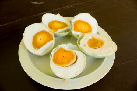salted duck egg (telur asin)served in white plate isolated on wood background