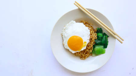 instant noodles served with egg fried and mustard greens on plate. instant fried noodle indomieの写真素材