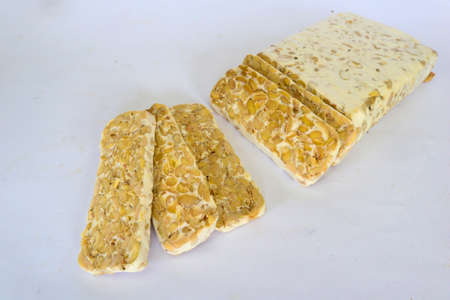 Raw tempeh or tempe. tempeh slices in white background. raw soybean seeds. Tempe is a traditional...