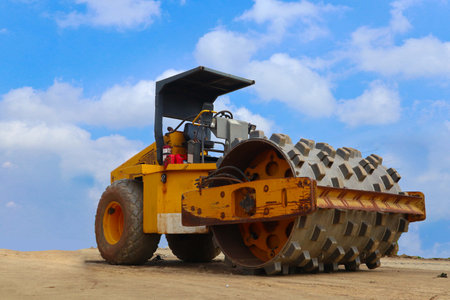 road roller with yellow color, on construction site and sky background
