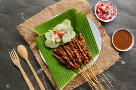 chicken satay or chicken satay served with lontong, rice cake and peanut sauce. served on banana leaveの写真素材