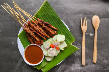 chicken satay or chicken satay served with lontong, rice cake and peanut sauce. served on banana leaveの写真素材