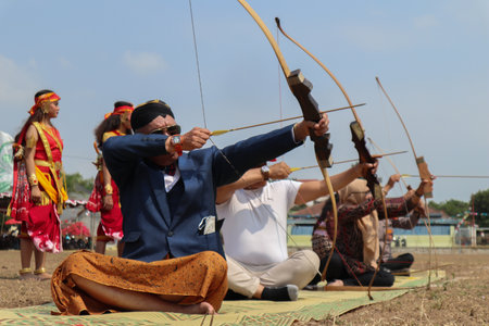 Klaten, Indonesia, august 15, 2023. male and female participants, dressed in Javanese custom pulled his bow by squinting to achieve concentration of target accuracy in traditional Javanese arrow tradのeditorial素材