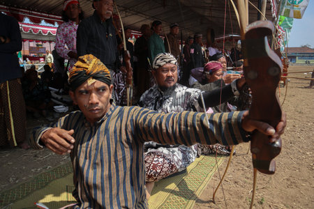 Klaten, Indonesia, august 15, 2023. male and female participants, dressed in Javanese custom pulled his bow by squinting to achieve concentration of target accuracy in traditional Javanese arrow tradのeditorial素材