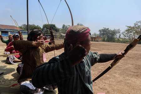 Klaten, Indonesia, august 15, 2023. male and female participants, dressed in Javanese custom pulled his bow by squinting to achieve concentration of target accuracy in traditional Javanese arrow tradのeditorial素材
