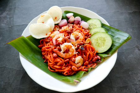 Mi Aceh, Mie Aceh or Acehnese noodles is a spicy dish typical of Aceh consisting of thick yellow noodles, slices of beef, mutton or shrimp, sliced ââred onions, cucumbers with a savory and spicy curry sauce. on tableの写真素材