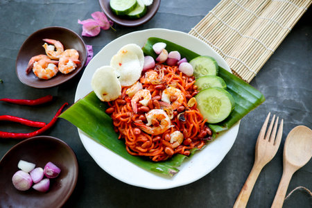 Mi Aceh, Mie Aceh or Acehnese noodles is a spicy dish typical of Aceh consisting of thick yellow noodles, slices of beef, mutton or shrimp, sliced ââred onions, cucumbers with a savory and spicy curry sauce. on tableの写真素材