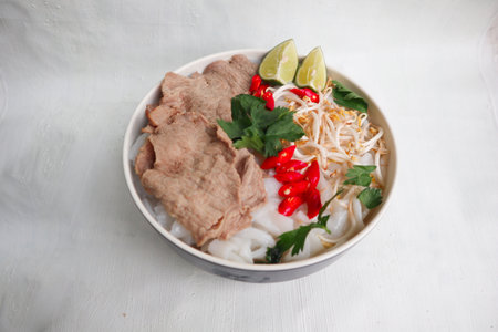 A Bowl Pho Bo traditional Soup with beef, rice noodles, ginger, lime, chili pepper in bowl. Close up. Vietnamese cuisine served on black backgroundの写真素材