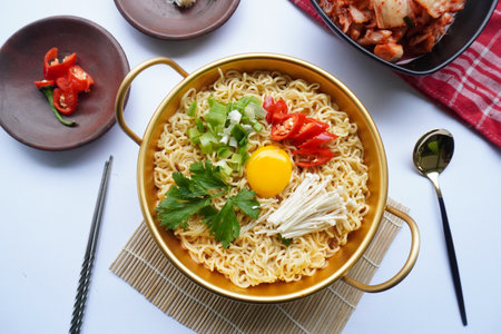 Ramyeon or Ramyun is Korean instant noodle, with spicy flavour topped with egg yolk, chilli, mushroom, kimchi inside a traditional korean noodle pot. Serving a Korean styleの写真素材