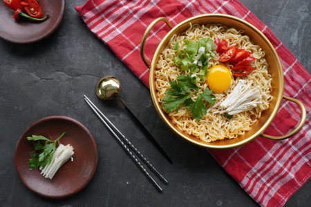 Ramyeon or Ramyun is Korean instant noodle, with spicy flavour topped with egg yolk, chilli, mushroom, kimchi inside a traditional korean noodle pot. Serving a Korean styleの写真素材