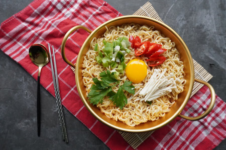 Ramyeon or Ramyun is Korean instant noodle, with spicy flavour topped with egg yolk, chilli, mushroom, kimchi inside a traditional korean noodle pot. Serving a Korean styleの写真素材