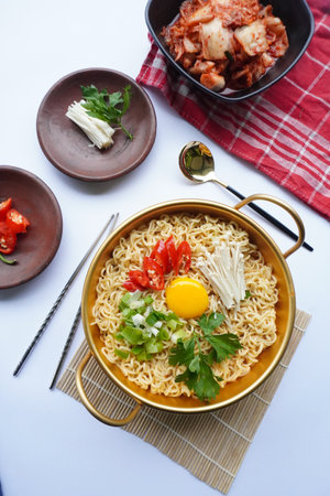 Ramyeon or Ramyun is Korean instant noodle, with spicy flavour topped with egg yolk, chilli, mushroom, kimchi inside a traditional korean noodle pot. Serving a Korean styleの写真素材