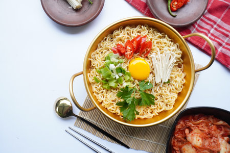 Ramyeon or Ramyun is Korean instant noodle, with spicy flavour topped with egg yolk, chilli, mushroom, kimchi inside a traditional korean noodle pot. Serving a Korean styleの写真素材