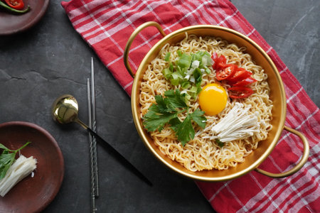 Ramyeon or Ramyun is Korean instant noodle, with spicy flavour topped with egg yolk, chilli, mushroom, kimchi inside a traditional korean noodle pot. Serving a Korean styleの写真素材