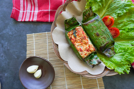 Nasi bakar is an Indonesian food, rice wrapped in banana leaves and then grilled. Rice filled with spices, chili sauce, shredded chicken, meat or fish.の写真素材
