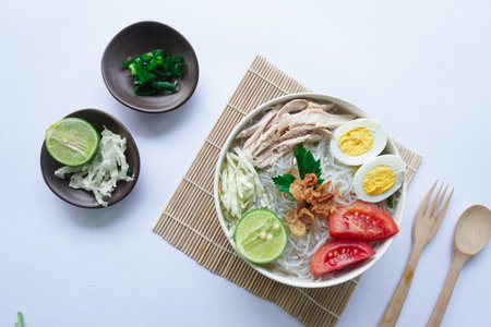 soto ayam bening or chicken soup is Indonesian food, made from rice, chicken broth, shredded chicken, boiled eggs, rice ,cabbage, vermicelli, tomatoes, celery and limeの写真素材