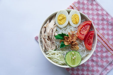 soto ayam bening or chicken soup is Indonesian food, made from rice, chicken broth, shredded chicken, boiled eggs, rice ,cabbage, vermicelli, tomatoes, celery and limeの写真素材