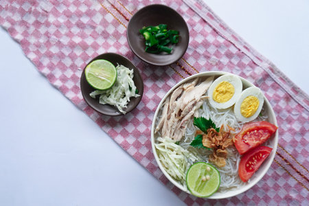 soto ayam bening or chicken soup is Indonesian food, made from rice, chicken broth, shredded chicken, boiled eggs, rice ,cabbage, vermicelli, tomatoes, celery and limeの写真素材