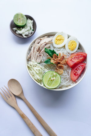 soto ayam bening or chicken soup is Indonesian food, made from rice, chicken broth, shredded chicken, boiled eggs, rice ,cabbage, vermicelli, tomatoes, celery and limeの写真素材